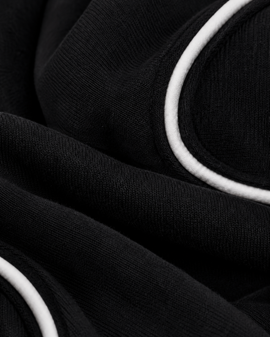 Macro detail of matte white textile piping inserted into the black panel seam.