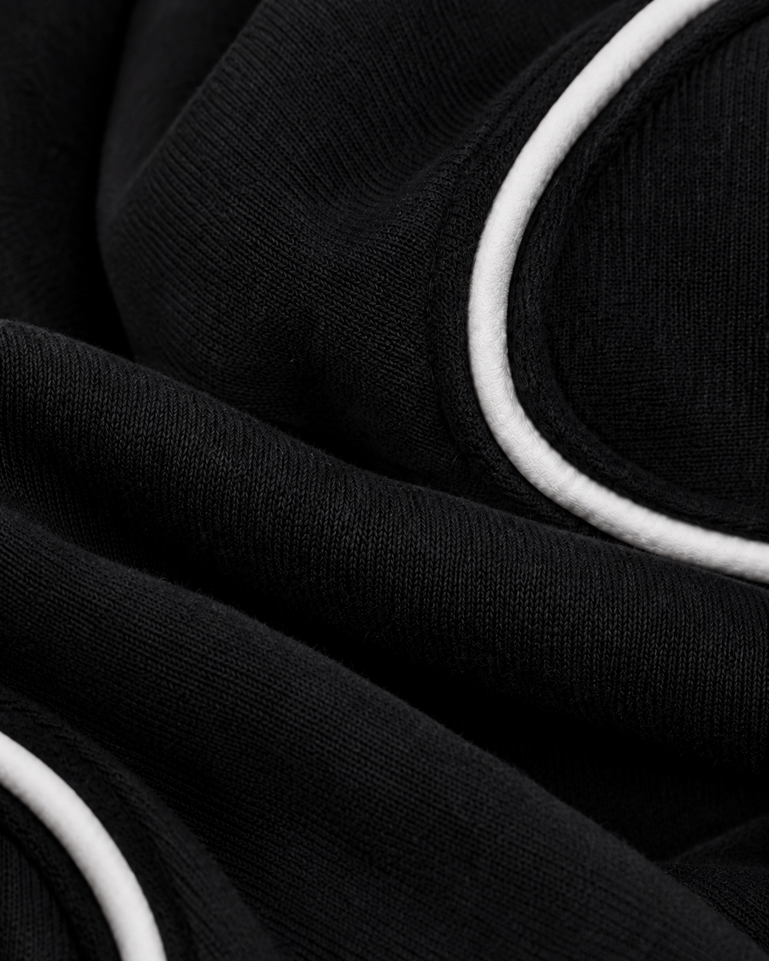 Macro detail of matte white textile piping inserted into the black panel seam.